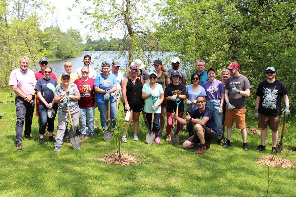 Siemens Peterborough employees posing in front of a newly planted tree